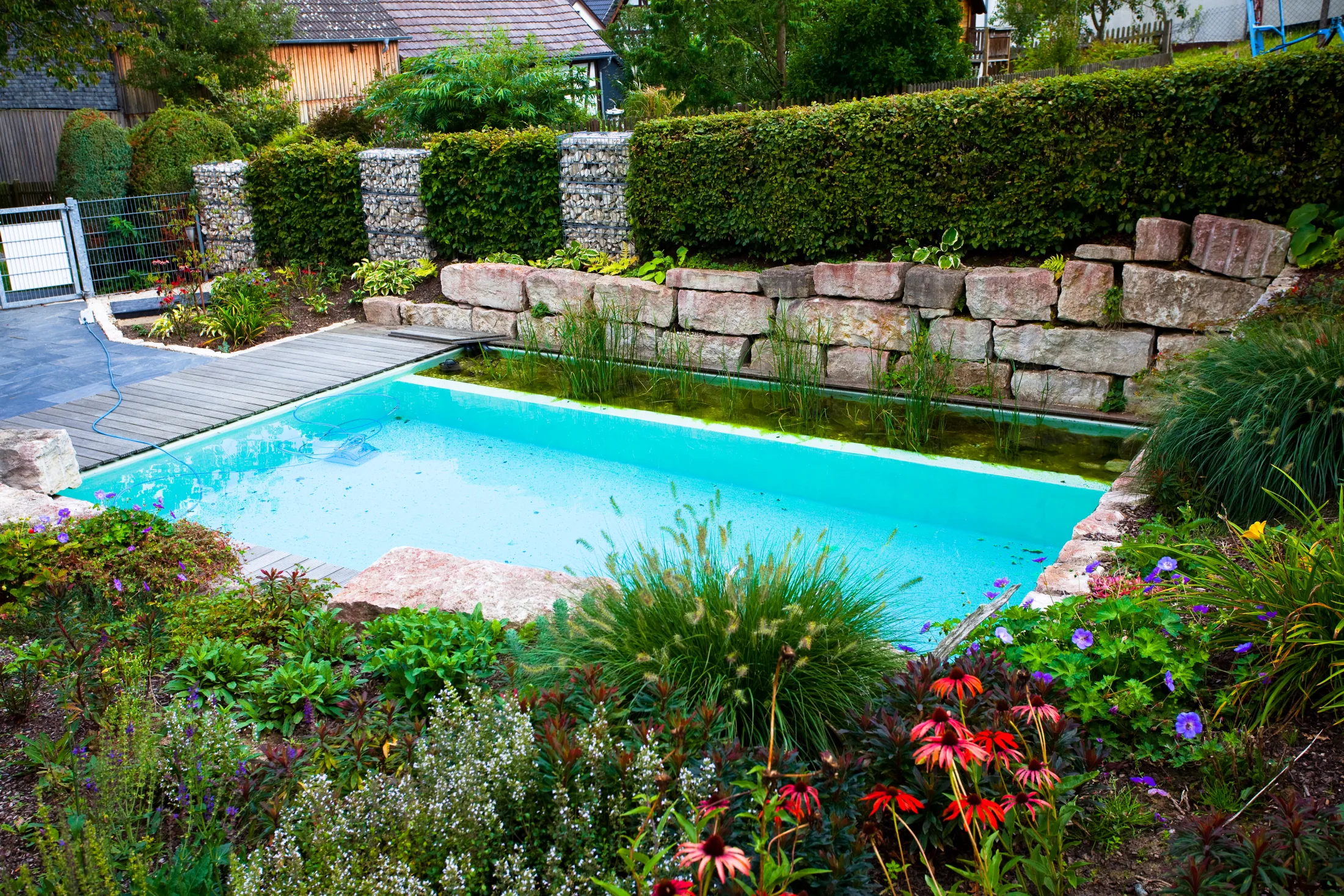 Naturpool mit Natursteinmauer und blühender Bepflanzung