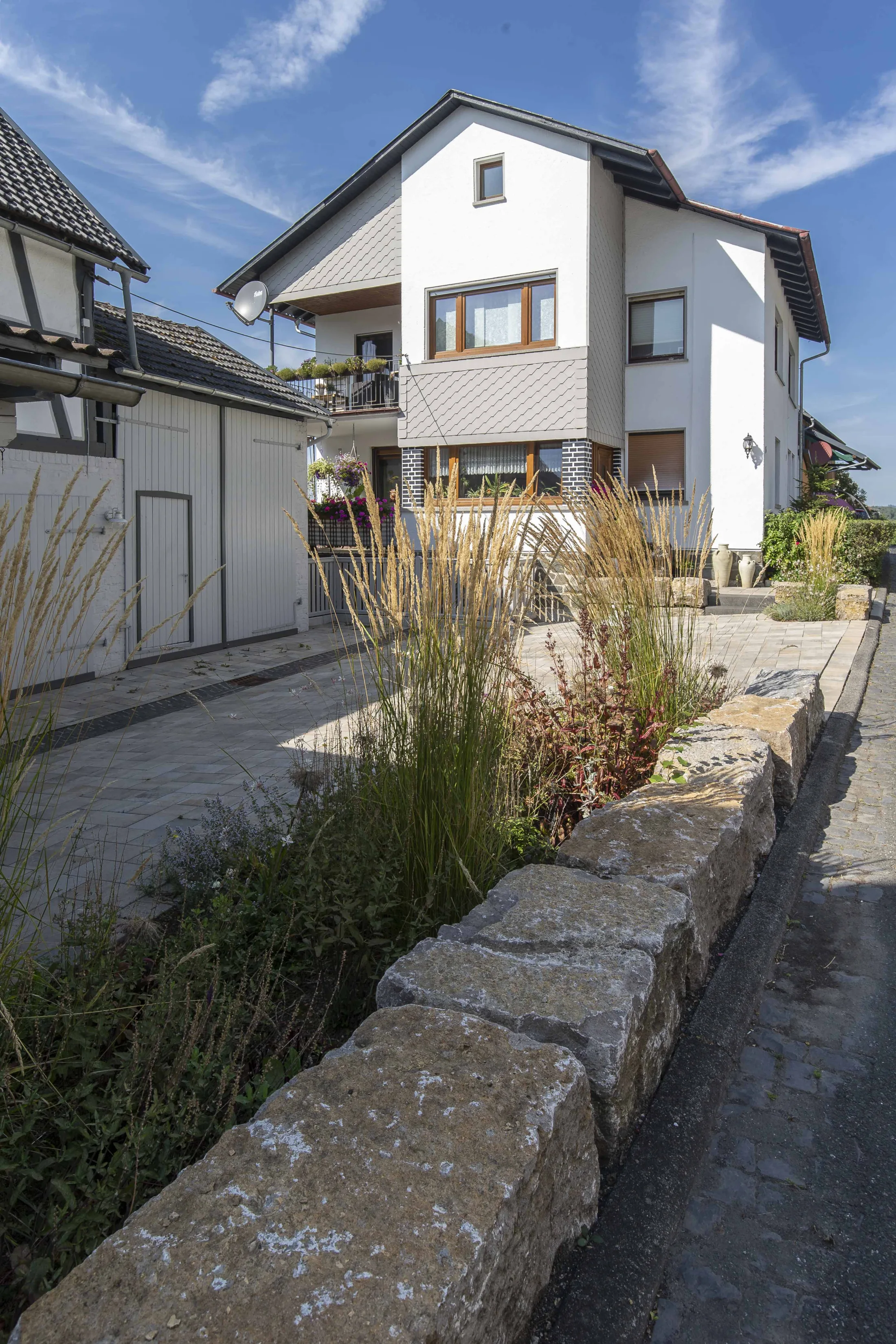 Natursteinmauer mit Gräserbepflanzung als naturnahe Gartengestaltung