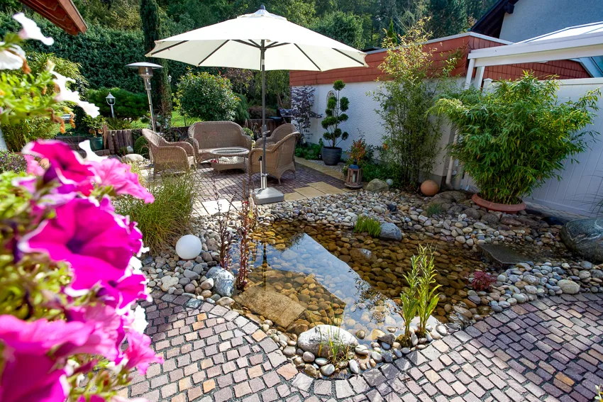 Holzterrasse am gepflegten Gartenteich mit Uferbepflanzung